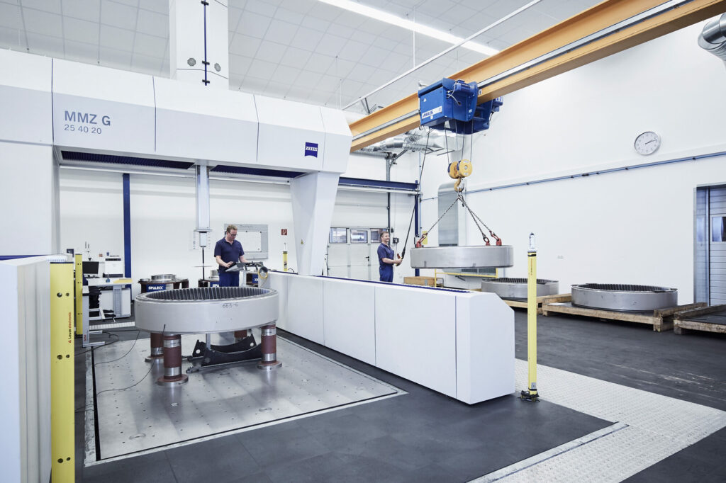 Meetmachine MMZ G in een fabriekshal, waar twee personen aan het werk zijn.