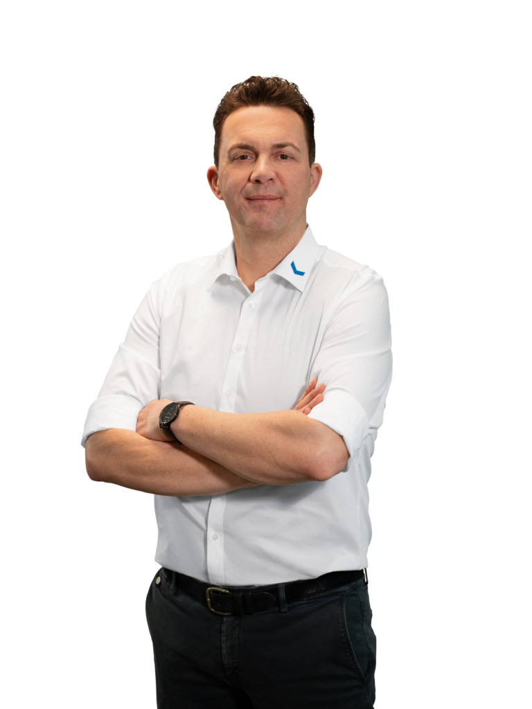Een man in een wit overhemd met zijn armen over elkaar voor een neutrale achtergrond.