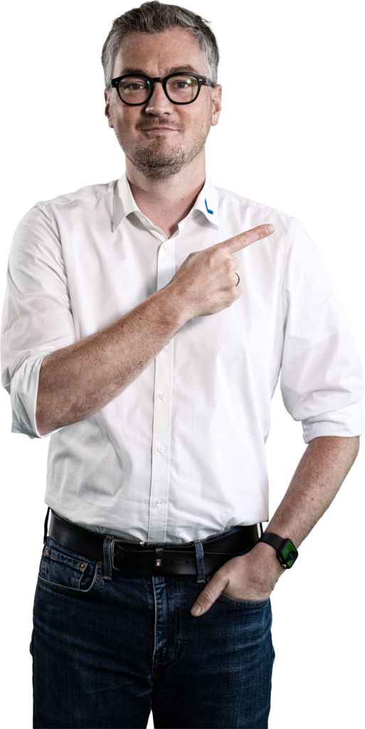 Een man in een wit overhemd en een spijkerbroek wijst met zijn vinger naar de zijkant.