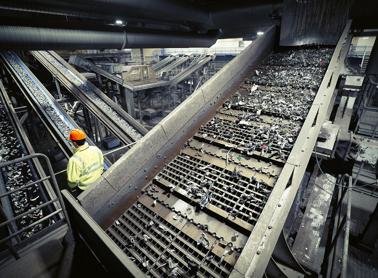 Een medewerker houdt toezicht op de transportband in een recyclinginstallatie.