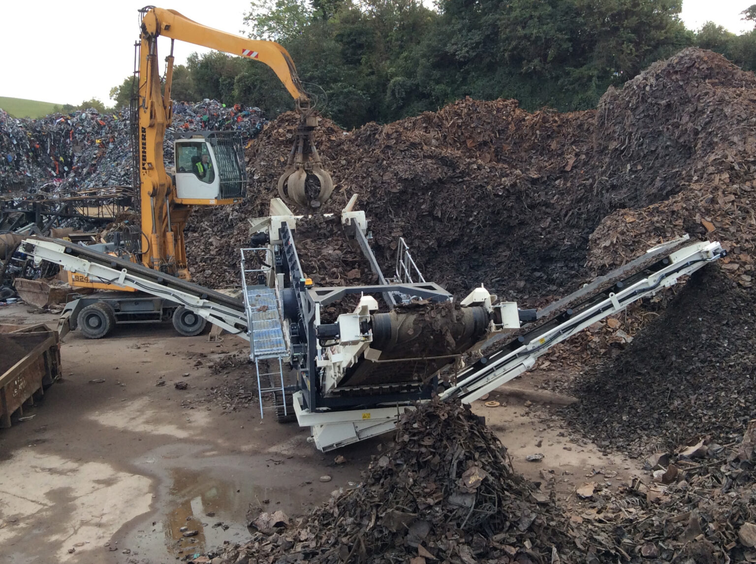 Mobiele zeefinstallaties bij de verwerking van schroot op een recyclinglocatie.