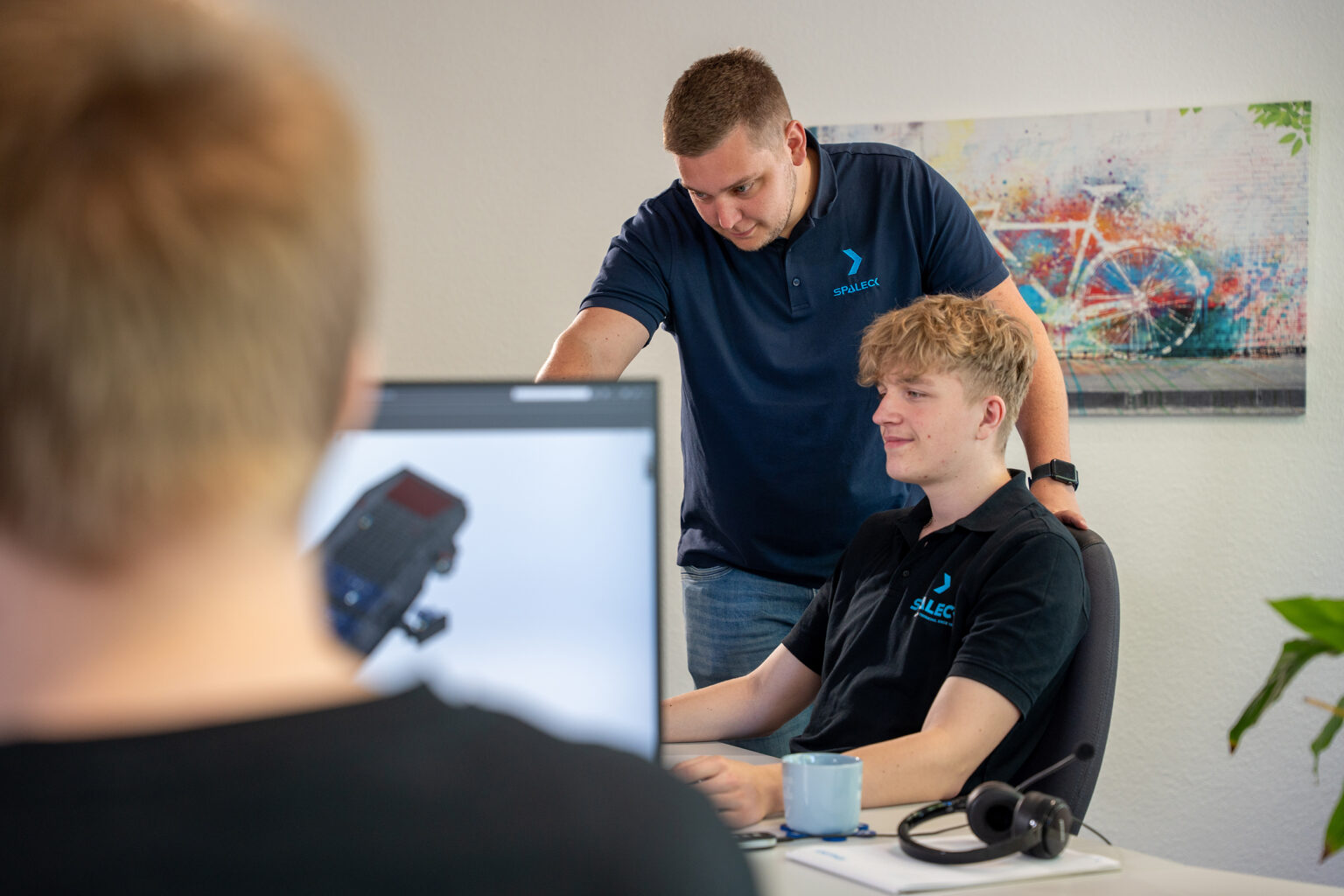 Een collega laat een stagiair voor technisch productontwerper iets zien op het scherm