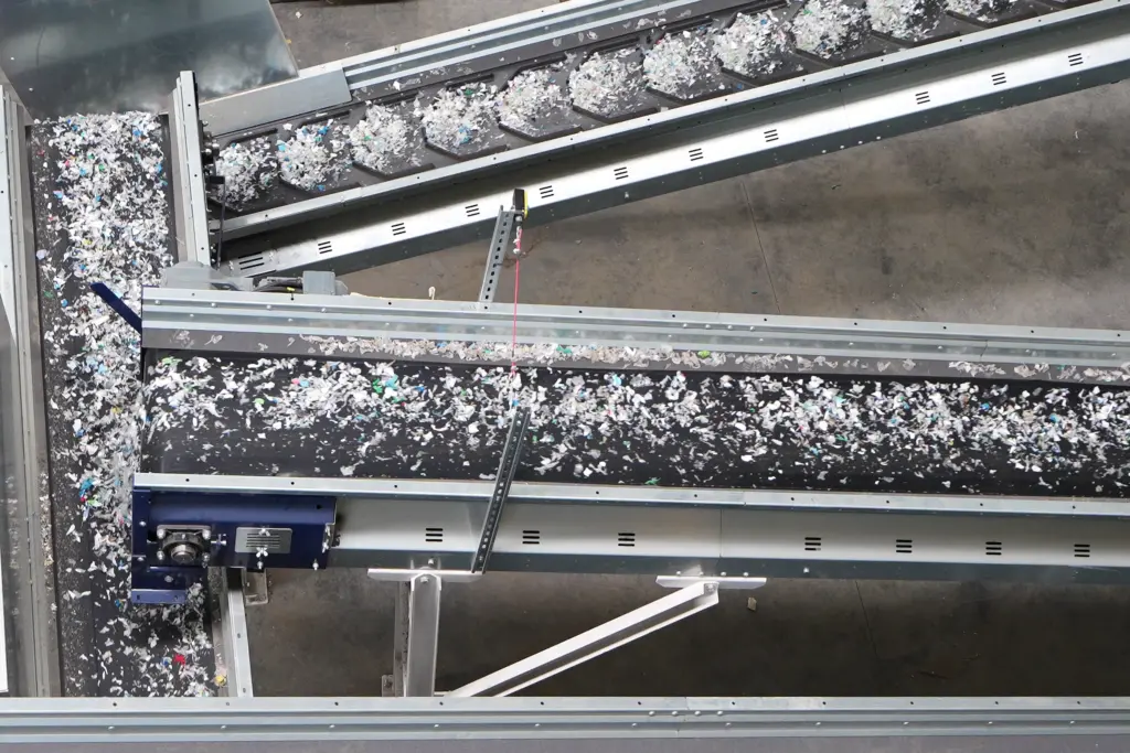 Transportbanden met kunststofafval dat door SPALECK-zeefmachines op grootte is gezeefd en dat vervolgens voor verdere sortering naar NIR-sorteermachines wordt getransporteerd.