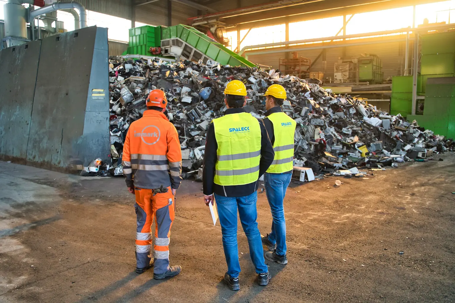 De projectleider van Immark en twee zeefmachine-experts van SPALECK staan voor het onvermalen inputmateriaal voor de nieuwe verwerkingsinstallatie voor elektronisch afval