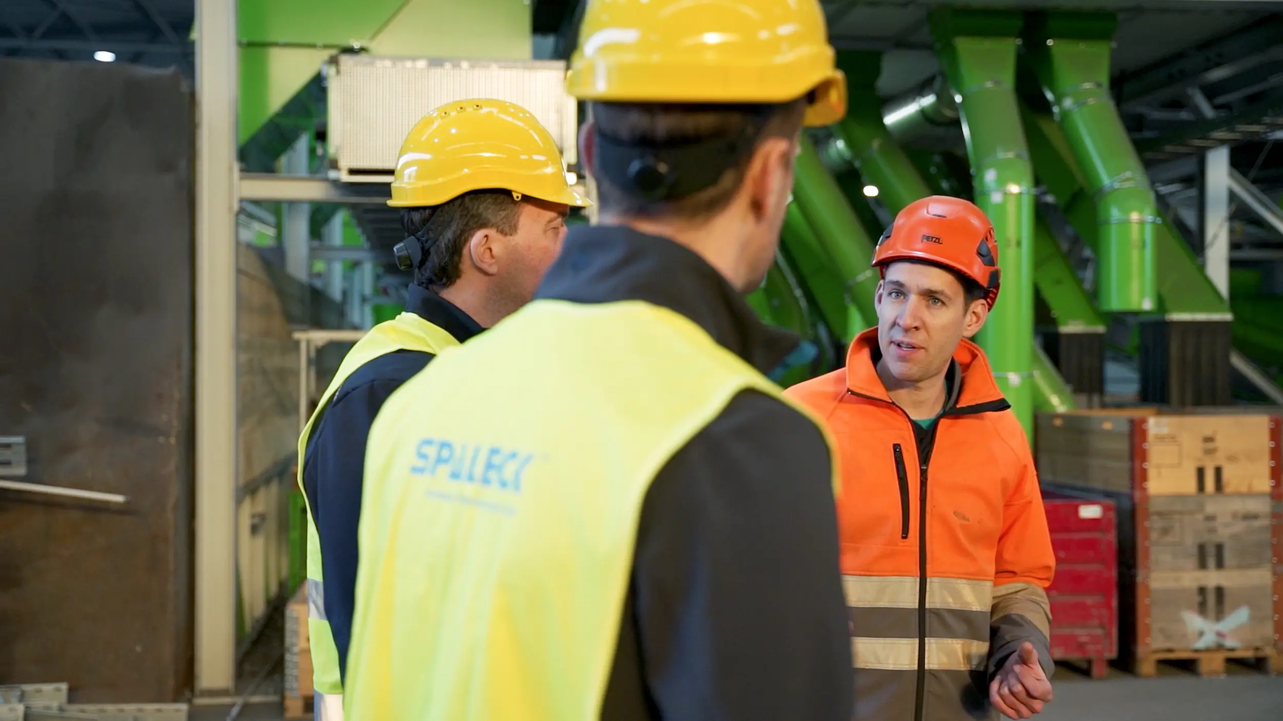 Medewerkers in beschermende kleding overleggen in een recyclinginstallatie.