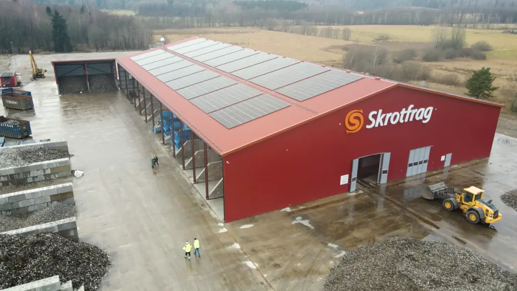 Skrotfrag-recyclinginstallatie voor non-ferrometalen met een rood gebouw en zonnepanelen.