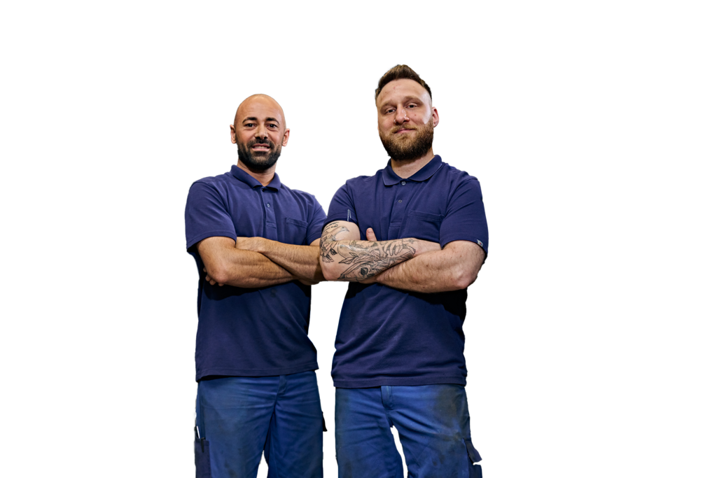 Twee mannen in werkkleding staan zelfverzekerd naast elkaar.