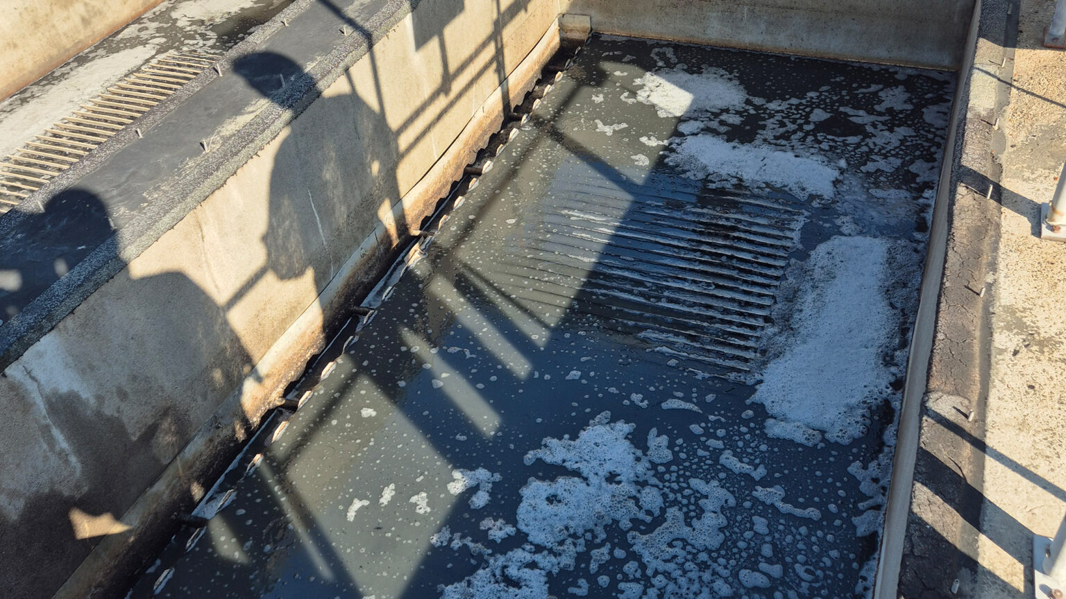 Bassin met afvalwater waarin zich vlokken en schuim met verontreinigingen vormen.