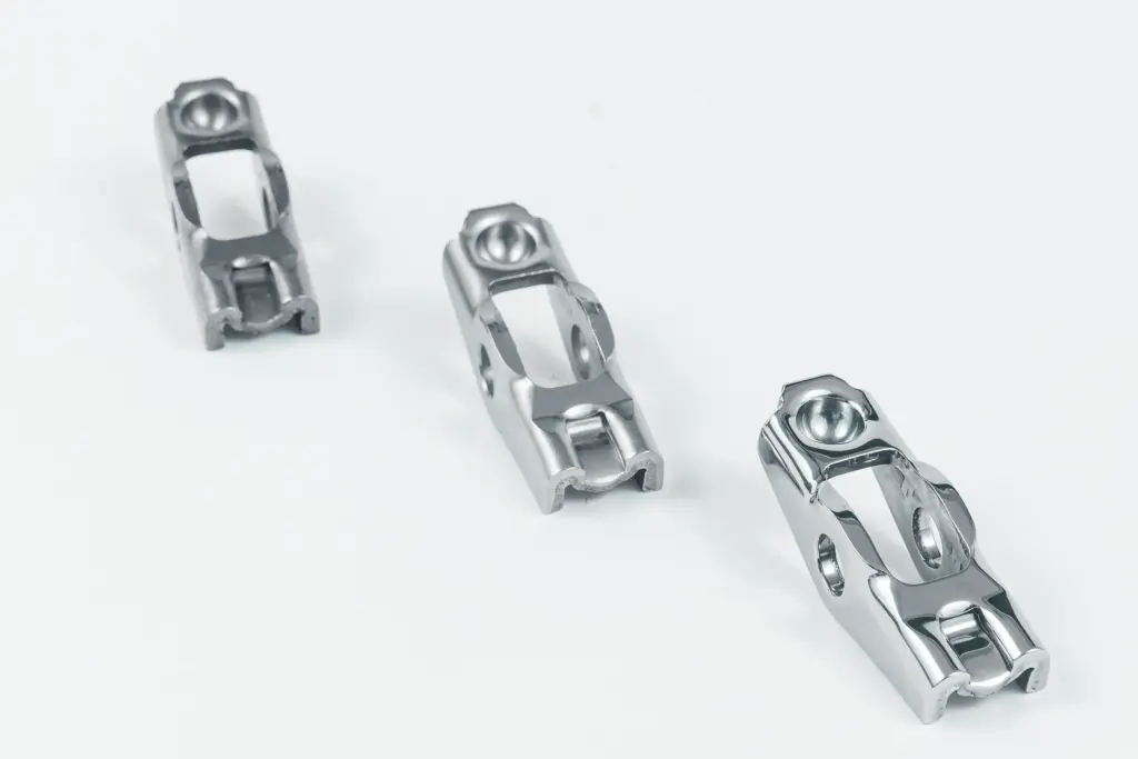 Drie glanzende metalen onderdelen na het glijslippen op een witte achtergrond.