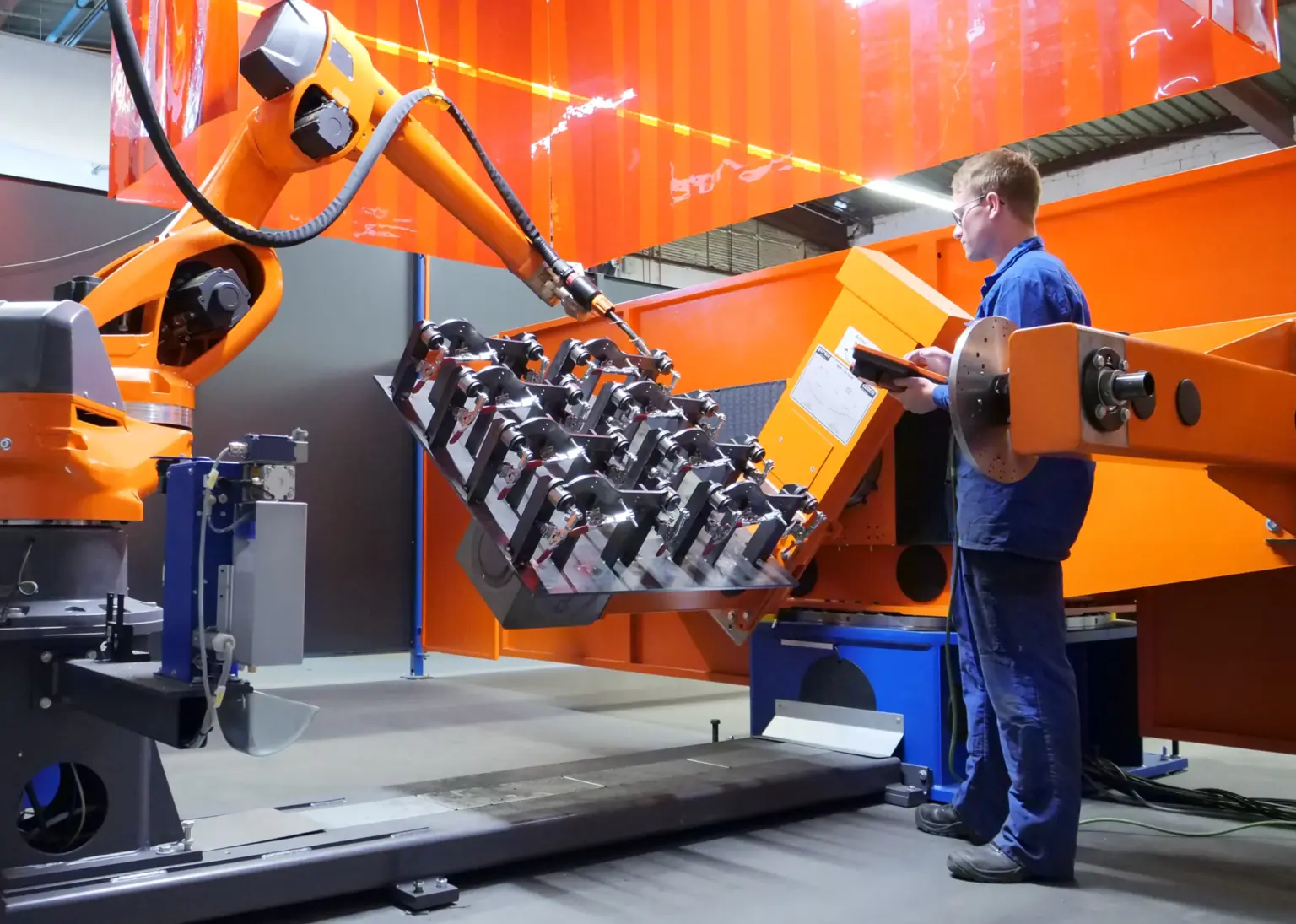 Een constructiemechanicus geeft instructies en traint een lasrobot in het lassen van een onderdeel bij loonfabrikant SPALECK