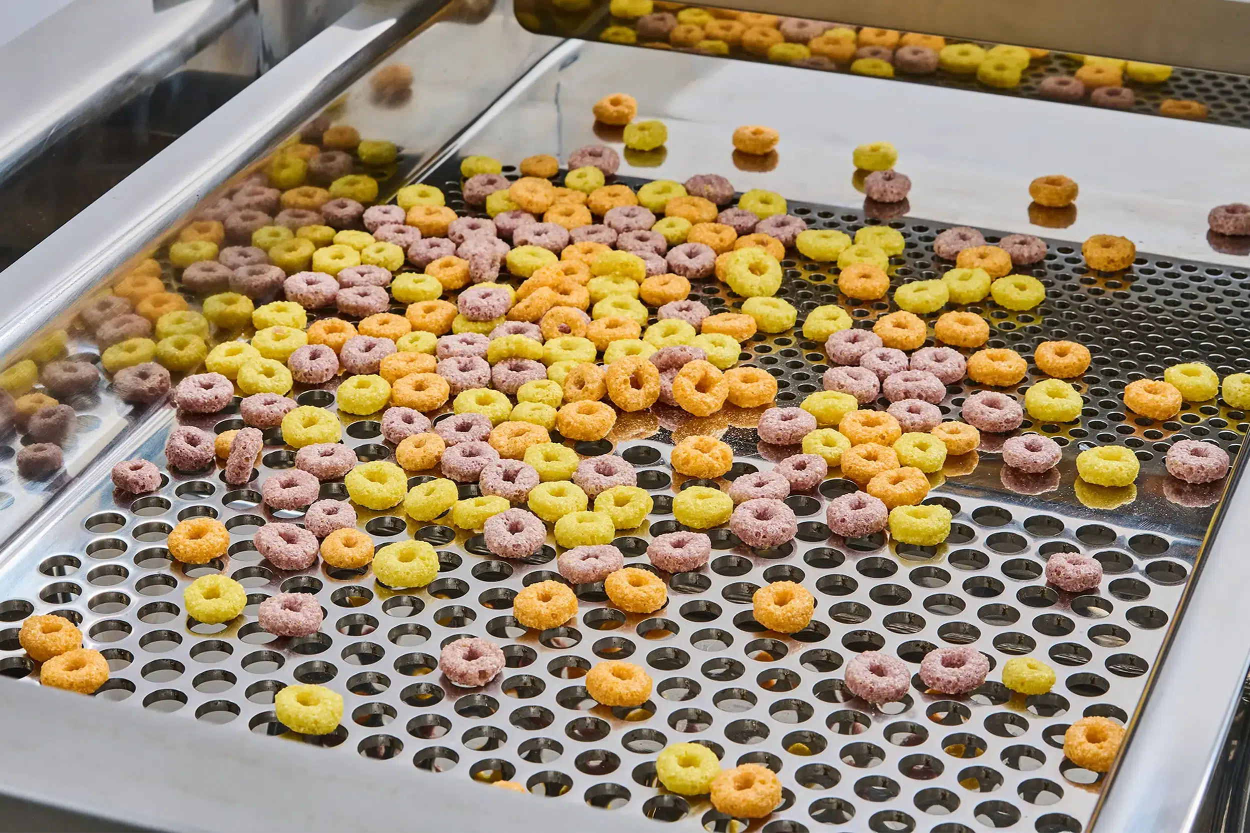 Zeefmachines voor levensmiddelen scheiden kleurrijke graanringen op een zeef.