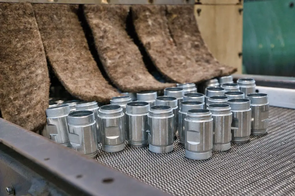 Metalen onderdelen op een transportband in een glijslibmachine.