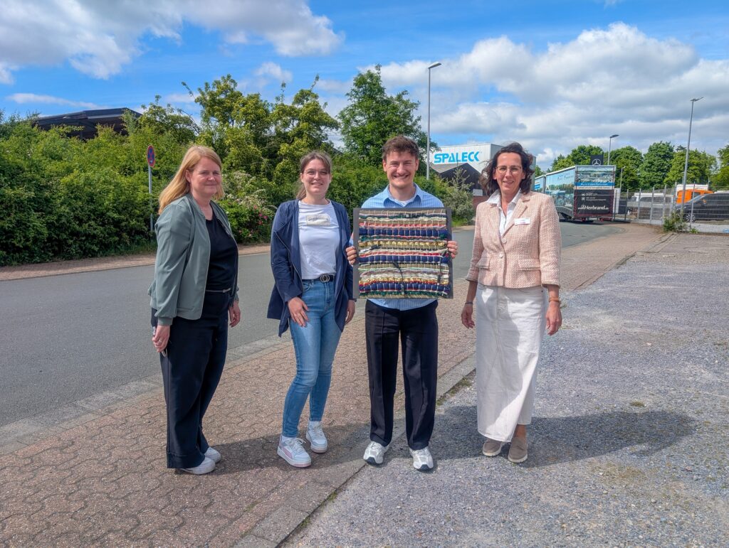 Twee teamleden van Spaleck houden een cadeau van collega’s van het Textielmuseum in Bocholt in hun handen