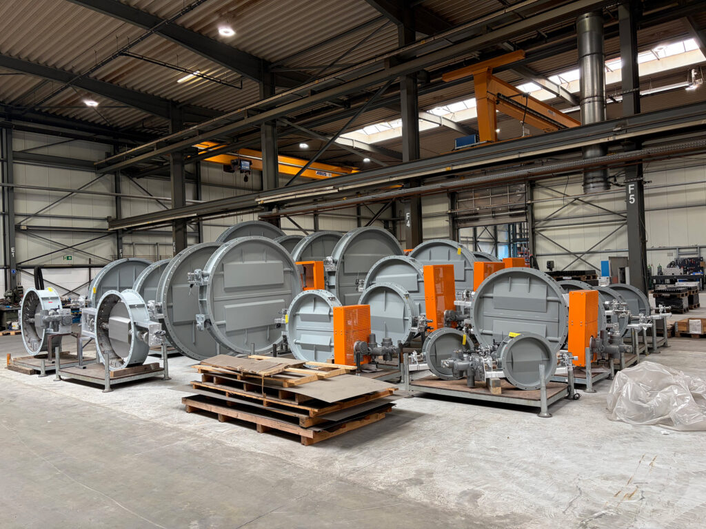 Overzicht van 25 industriële kleppen en schuifafsluiters in een productiehal, klaar voor oplevering aan een cementfabriek