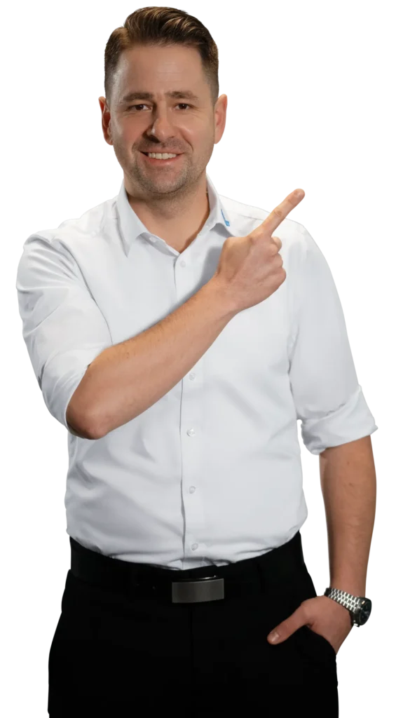 Een man in een wit overhemd wijst glimlachend naar de zijkant.