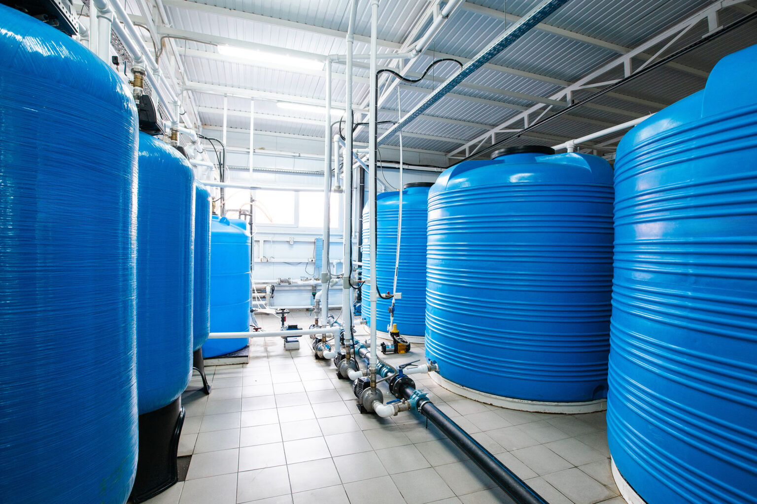 Verschillende grote blauwe tanks voor neerslag en flocculatie bij de waterzuivering in de industriële hal