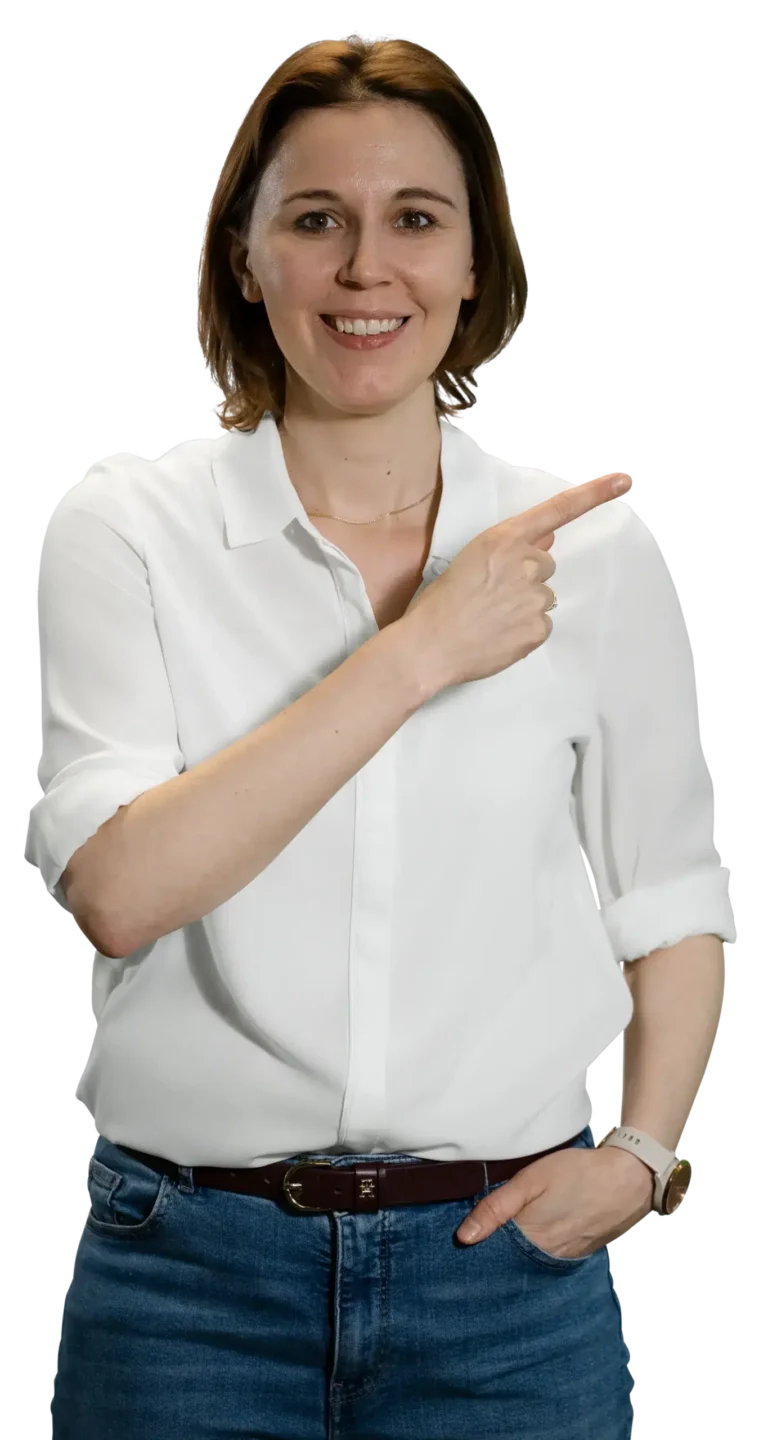 Een vrouw in een wit overhemd en een spijkerbroek wijst glimlachend naar de zijkant.