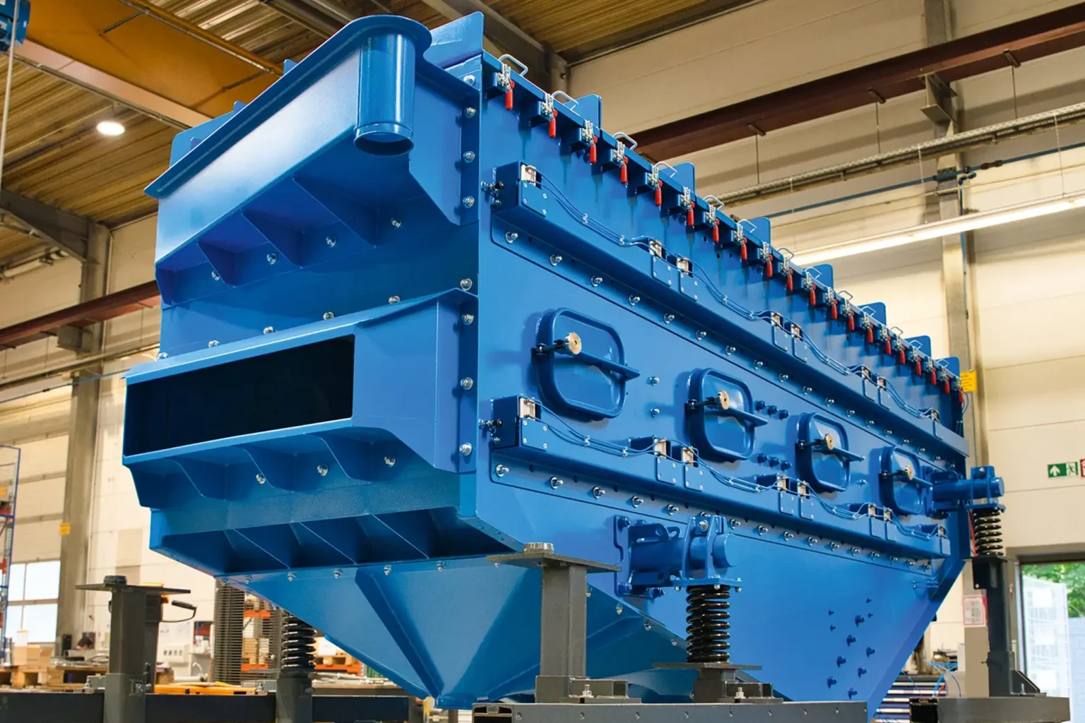 Grote blauwe metalen machine in een fabriekshal, geschikt voor OPPERVLAKTEBEHANDELING.