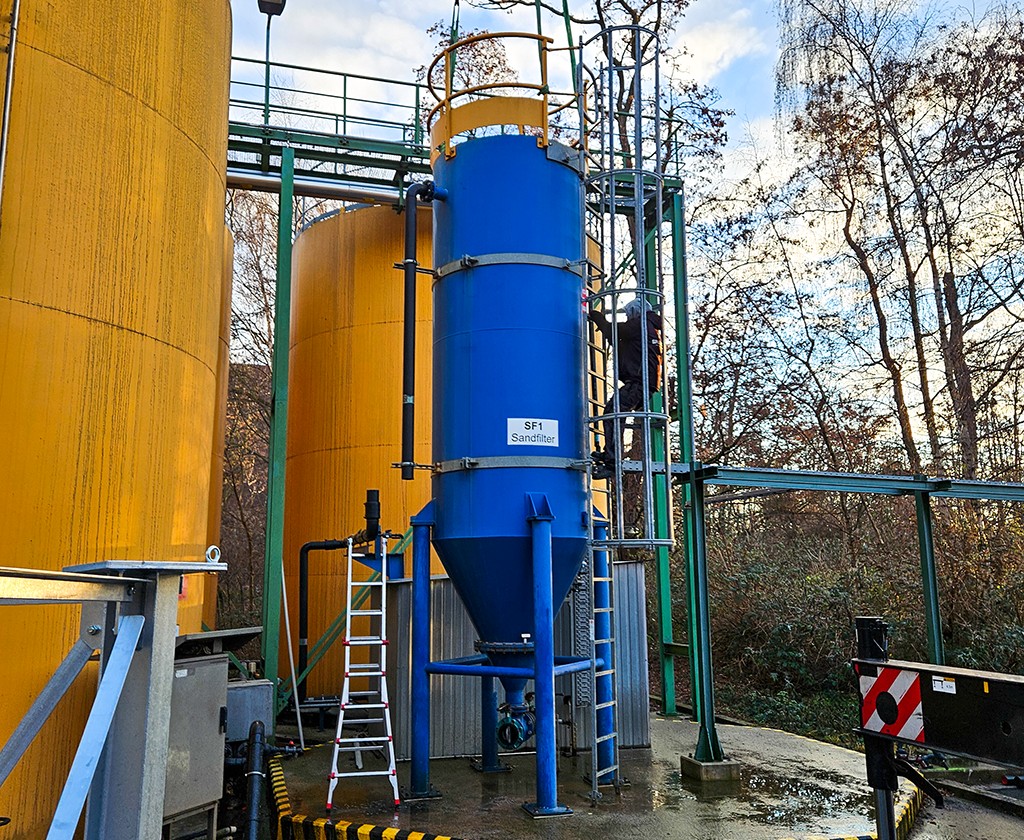 Blauwe tank voor zandfiltratie bij de waterzuivering, naast gele tanks.