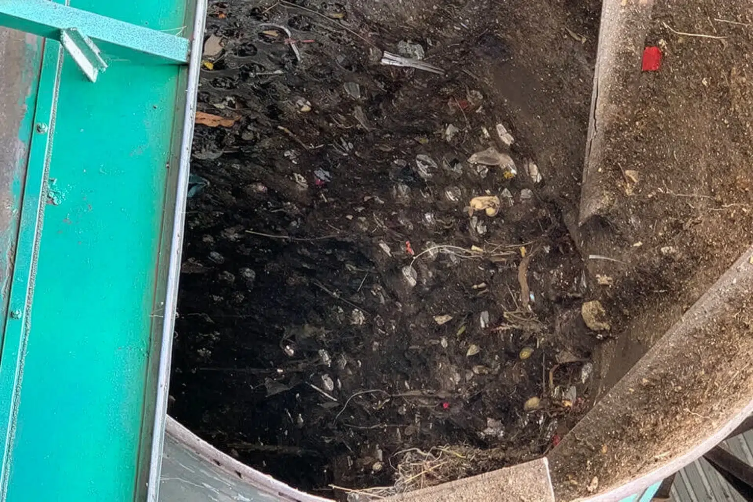 Een trommelzeef met aarde en organisch materiaal.
