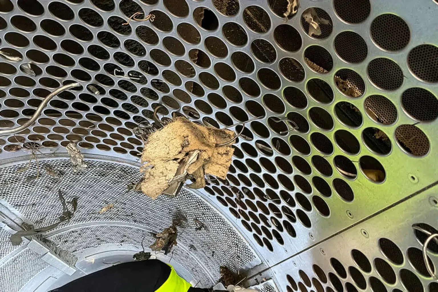 Een gedetailleerd beeld van het binnenwerk van een trommelzeefmachine. Je kunt goed zien dat er tijdens het doorroeren van het materiaal onbedoeld lange stukken in de doelfractie terecht kunnen komen.