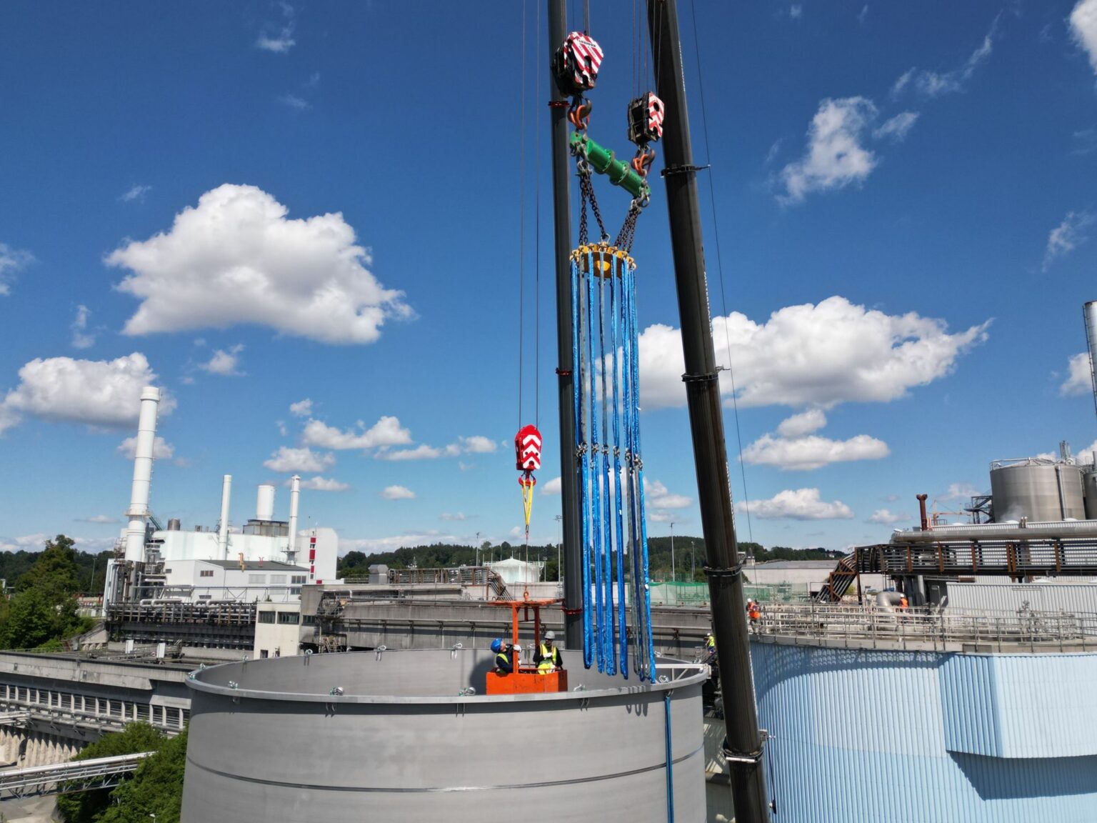 Installatie van een grote tank voor waterzuivering in de industrie met behulp van een kraan. Vakmensen zijn aan het werk in de tank